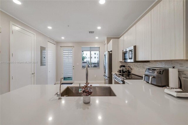 kitchen with tasteful backsplash, sink, ornamental molding, and stainless steel appliances