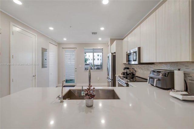 kitchen featuring tasteful backsplash, stainless steel appliances, crown molding, and sink