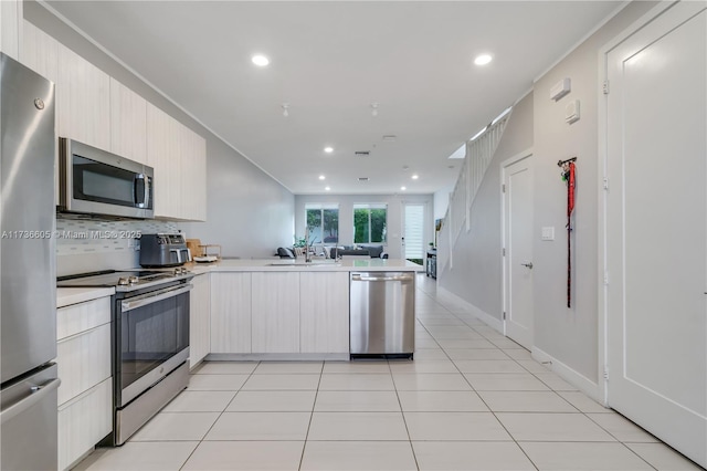 kitchen featuring sink, light tile patterned floors, kitchen peninsula, stainless steel appliances, and decorative backsplash