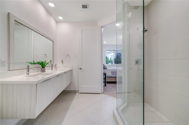 bathroom featuring tiled shower, vanity, and tile patterned flooring