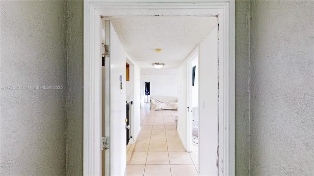 corridor featuring light tile patterned flooring and a textured ceiling