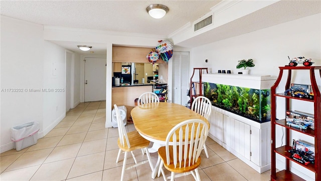 dining space featuring light tile patterned flooring, crown molding, and a textured ceiling