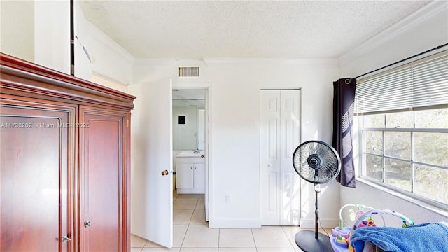 tiled bedroom with ornamental molding, a textured ceiling, and ensuite bath