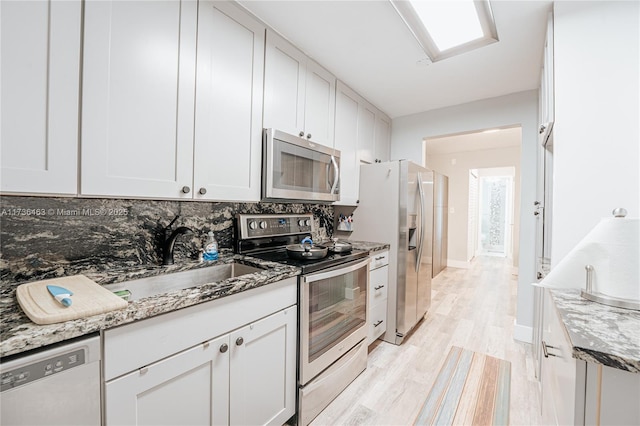 kitchen with stainless steel appliances, stone countertops, and white cabinets