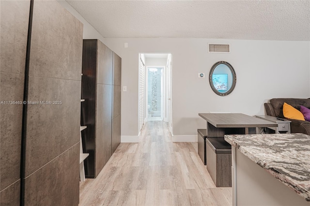 corridor featuring a textured ceiling and light hardwood / wood-style flooring