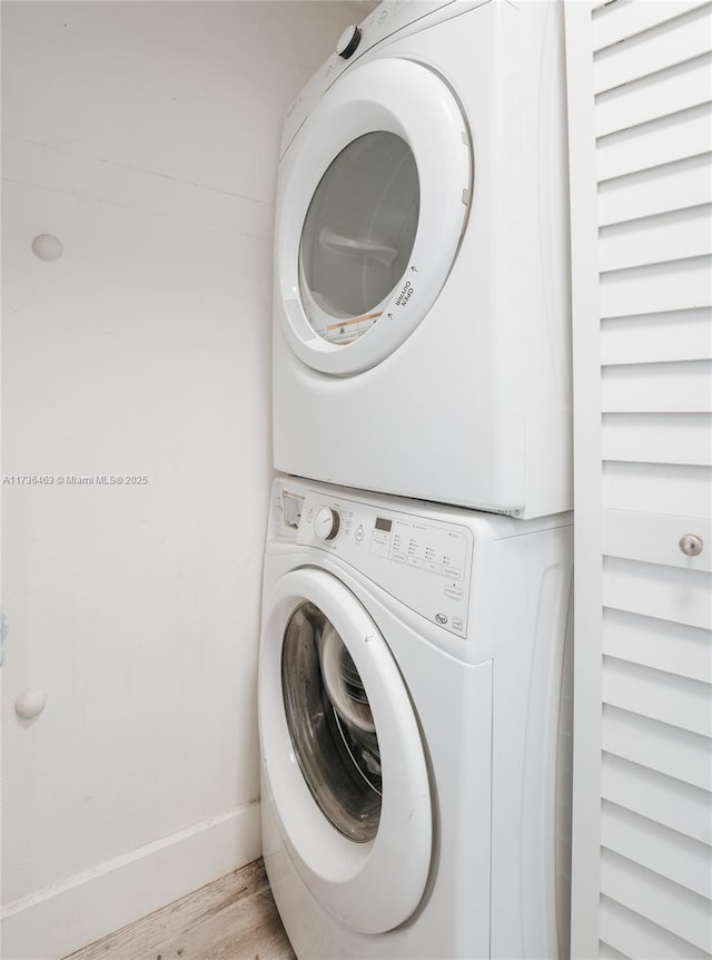 laundry area with stacked washer and dryer and light wood-type flooring