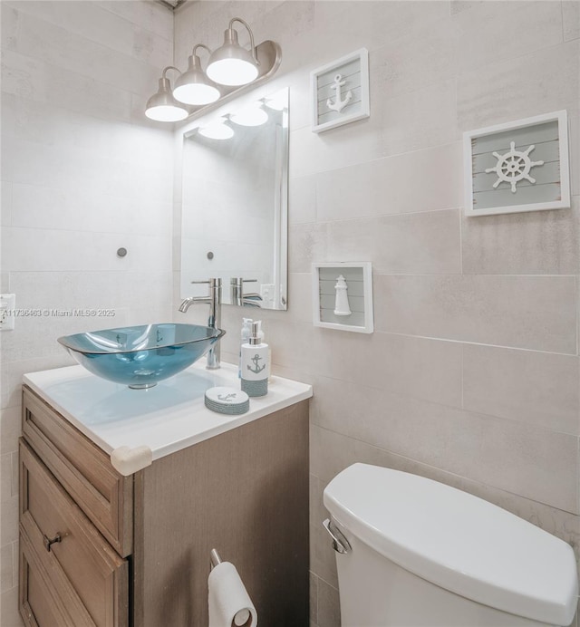 bathroom featuring vanity, tile walls, and toilet