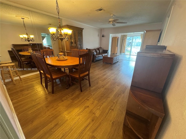 dining space with ceiling fan with notable chandelier, ornamental molding, hardwood / wood-style floors, and a textured ceiling