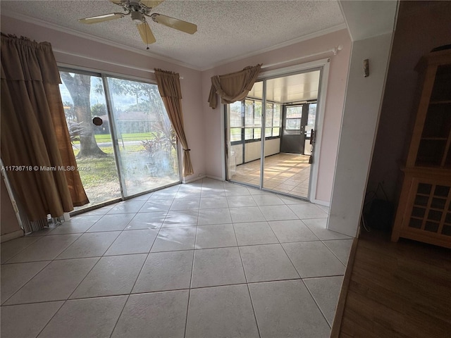 spare room with ornamental molding, a textured ceiling, and light tile patterned flooring