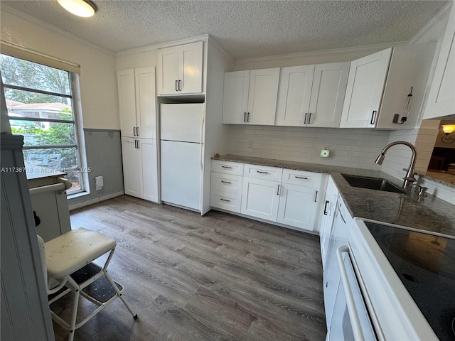 kitchen featuring sink, crown molding, white cabinetry, white refrigerator, and light wood-type flooring