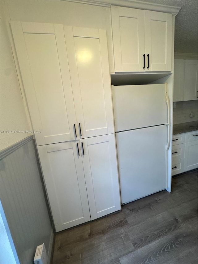 interior space with white fridge, dark wood-type flooring, and white cabinets