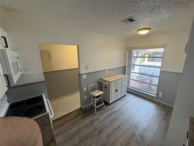 kitchen featuring white cabinetry, wooden counters, a textured ceiling, hardwood / wood-style floors, and white range with electric stovetop