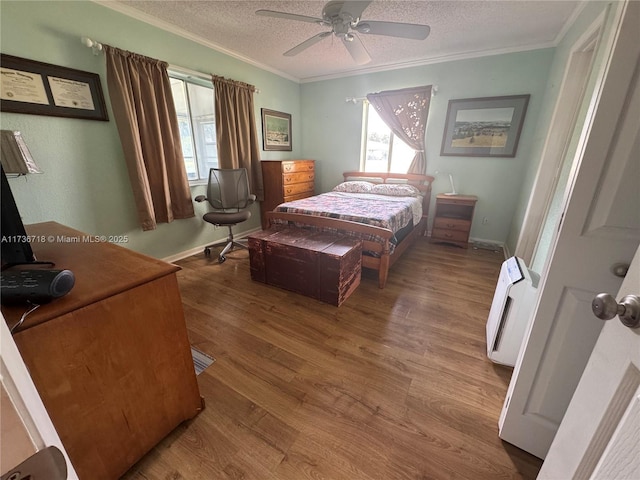 bedroom featuring multiple windows, crown molding, hardwood / wood-style floors, and a textured ceiling