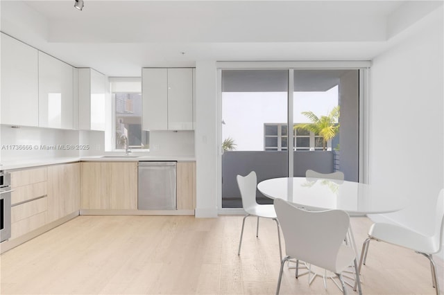 kitchen featuring sink, white cabinetry, stainless steel appliances, light hardwood / wood-style floors, and light brown cabinets