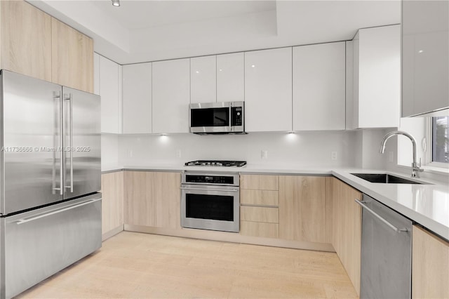 kitchen featuring sink, light hardwood / wood-style flooring, light brown cabinets, appliances with stainless steel finishes, and white cabinets