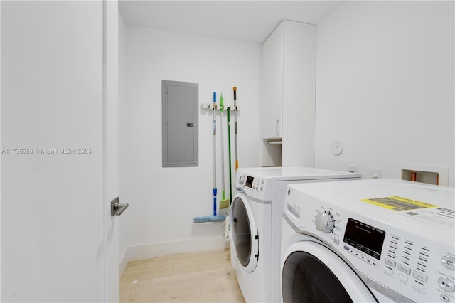 laundry area with cabinets, light hardwood / wood-style flooring, electric panel, and independent washer and dryer