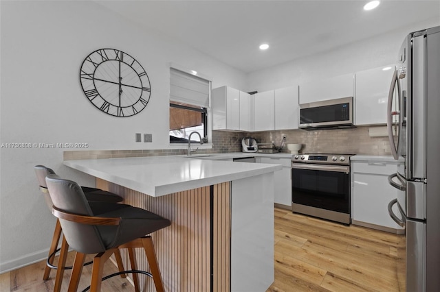 kitchen with stainless steel appliances, white cabinetry, tasteful backsplash, and a breakfast bar area