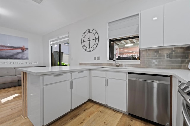 kitchen featuring white cabinetry, dishwasher, sink, decorative backsplash, and kitchen peninsula