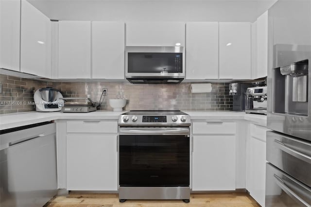 kitchen with stainless steel appliances, tasteful backsplash, white cabinets, and light hardwood / wood-style floors