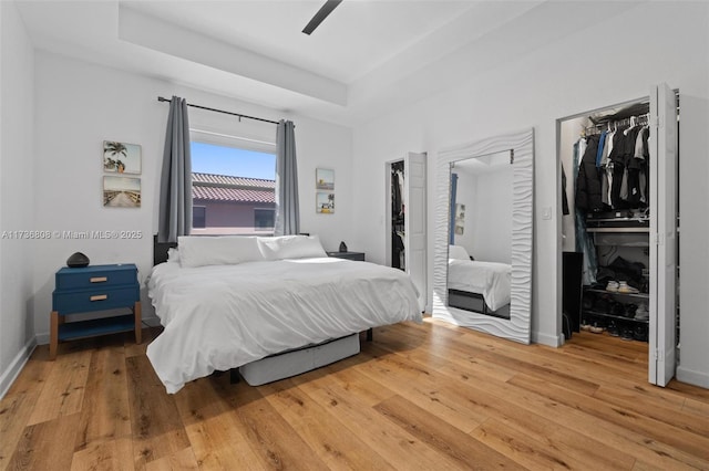 bedroom featuring hardwood / wood-style floors, ceiling fan, and a tray ceiling