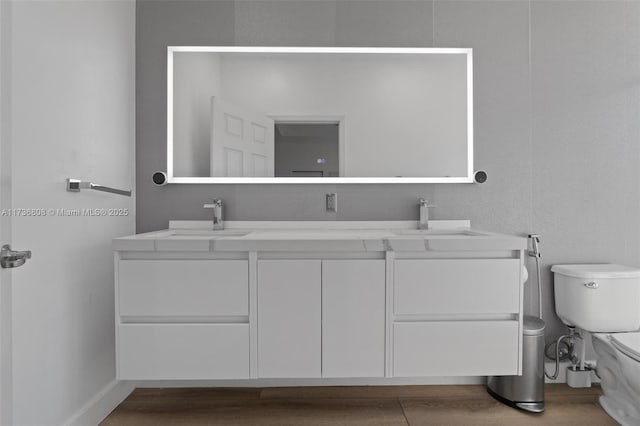 bathroom featuring wood-type flooring, vanity, and toilet