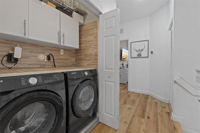 laundry room with washer and clothes dryer, light hardwood / wood-style floors, and cabinets