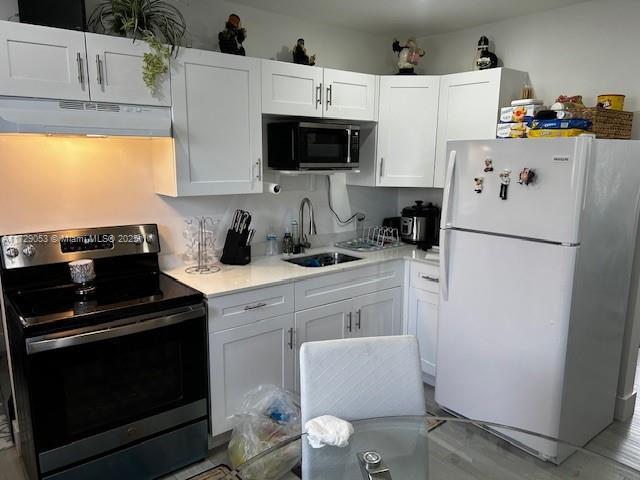 kitchen featuring white cabinetry, white fridge, sink, and stainless steel range with electric stovetop