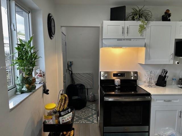 kitchen featuring light stone counters, hardwood / wood-style floors, electric range, and white cabinets