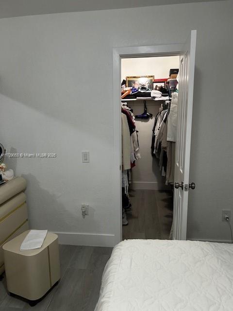 bedroom with a walk in closet, hardwood / wood-style floors, and a closet