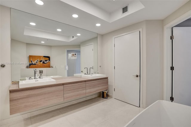 bathroom featuring vanity, a bath, tile patterned flooring, and a raised ceiling