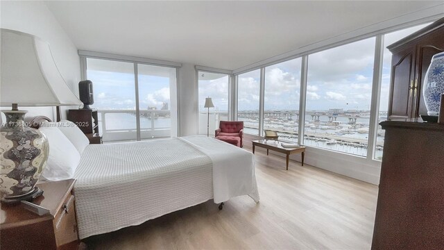 bedroom with a water view, light wood-style flooring, and multiple windows