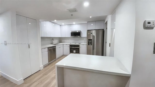 kitchen with modern cabinets, white cabinetry, stainless steel appliances, and light countertops