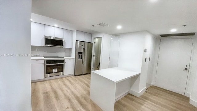 kitchen featuring stainless steel appliances, light countertops, light wood-style flooring, white cabinetry, and modern cabinets