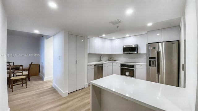 kitchen featuring visible vents, modern cabinets, stainless steel appliances, light countertops, and white cabinetry