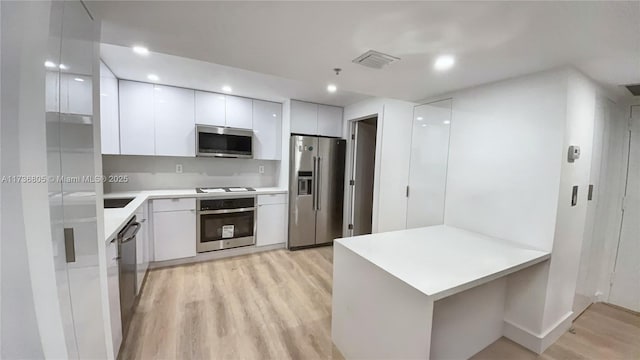 1717 N Bayshore Dr Unit A-1231, Miami, FL 33132 - kitchen featuring stainless steel appliances, modern cabinets, light wood-style flooring, a peninsula, and white cabinetry