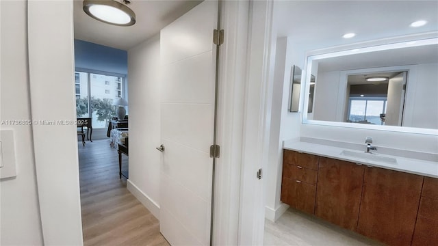 corridor featuring recessed lighting, a sink, and light wood finished floors