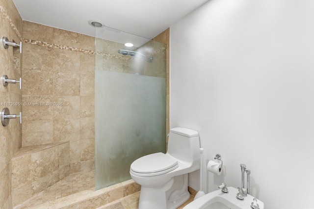 bathroom with a bidet, toilet, and tiled shower