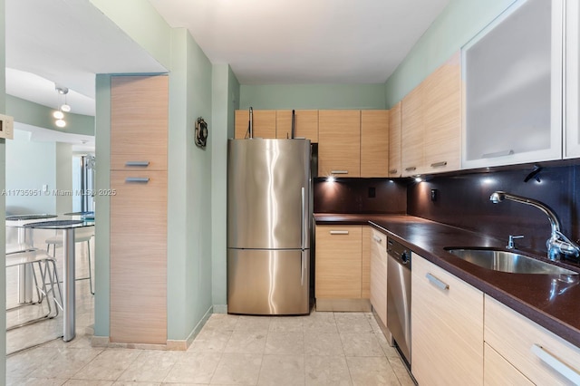 kitchen featuring light tile patterned flooring, light brown cabinetry, sink, stainless steel appliances, and decorative backsplash