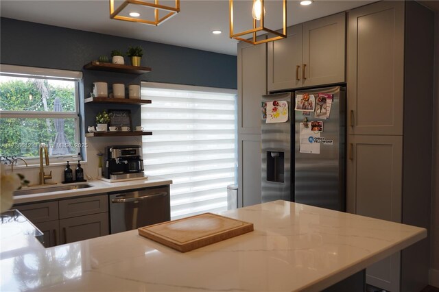 kitchen with appliances with stainless steel finishes, decorative light fixtures, light stone countertops, and gray cabinetry