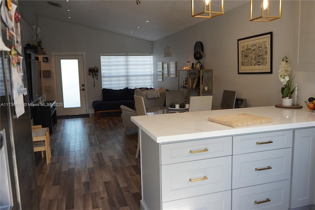 kitchen with vaulted ceiling, light stone counters, white cabinets, and decorative light fixtures