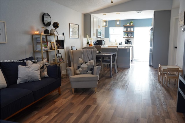 living area with vaulted ceiling, dark wood-style floors, and visible vents