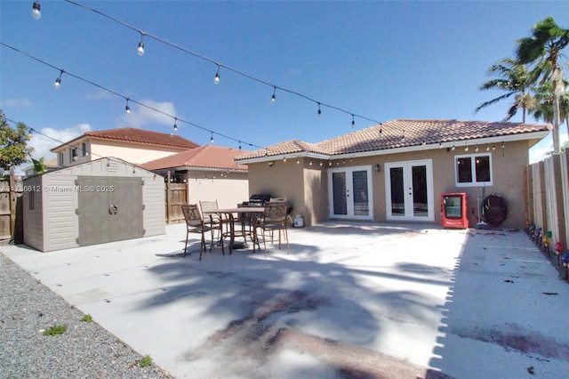 rear view of property featuring a tiled roof, french doors, a patio area, and fence