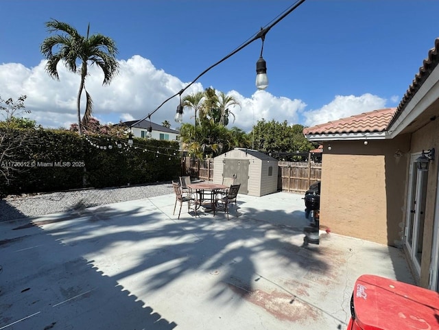 view of patio / terrace with a storage shed, outdoor dining space, an outbuilding, and a fenced backyard