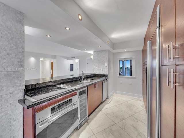 kitchen featuring appliances with stainless steel finishes, sink, dark stone countertops, and wine cooler