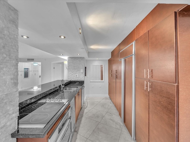 kitchen with stovetop, sink, dark stone countertops, stainless steel dishwasher, and paneled fridge