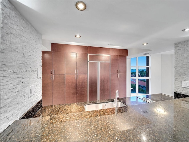 kitchen featuring black electric stovetop, sink, and dark stone countertops