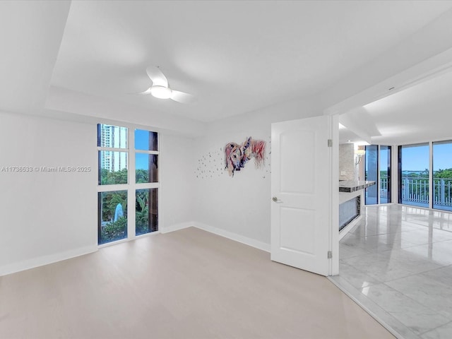 unfurnished room featuring ceiling fan and a wall of windows