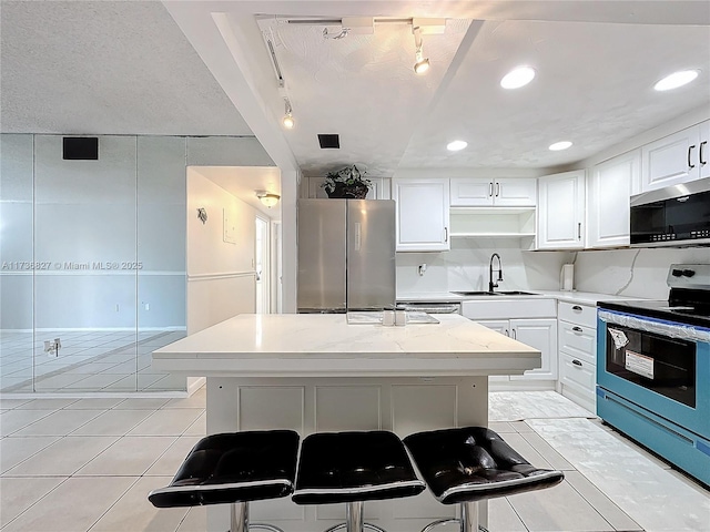 kitchen featuring sink, a kitchen breakfast bar, stainless steel appliances, a center island, and white cabinets