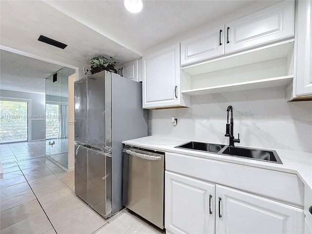 kitchen featuring sink, appliances with stainless steel finishes, white cabinetry, backsplash, and a textured ceiling