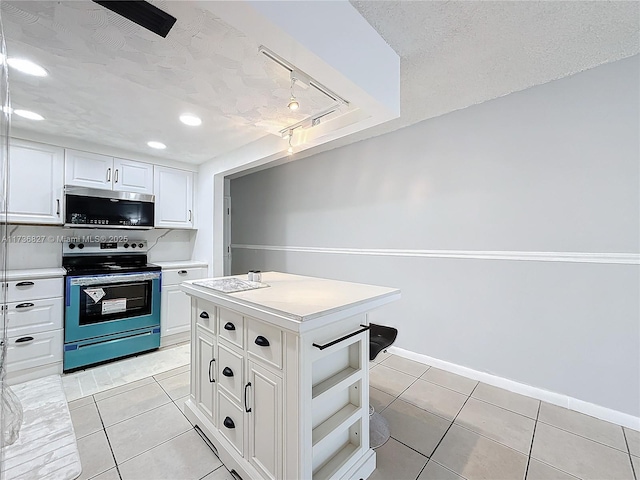 kitchen with light tile patterned floors, appliances with stainless steel finishes, a textured ceiling, a kitchen island, and white cabinets